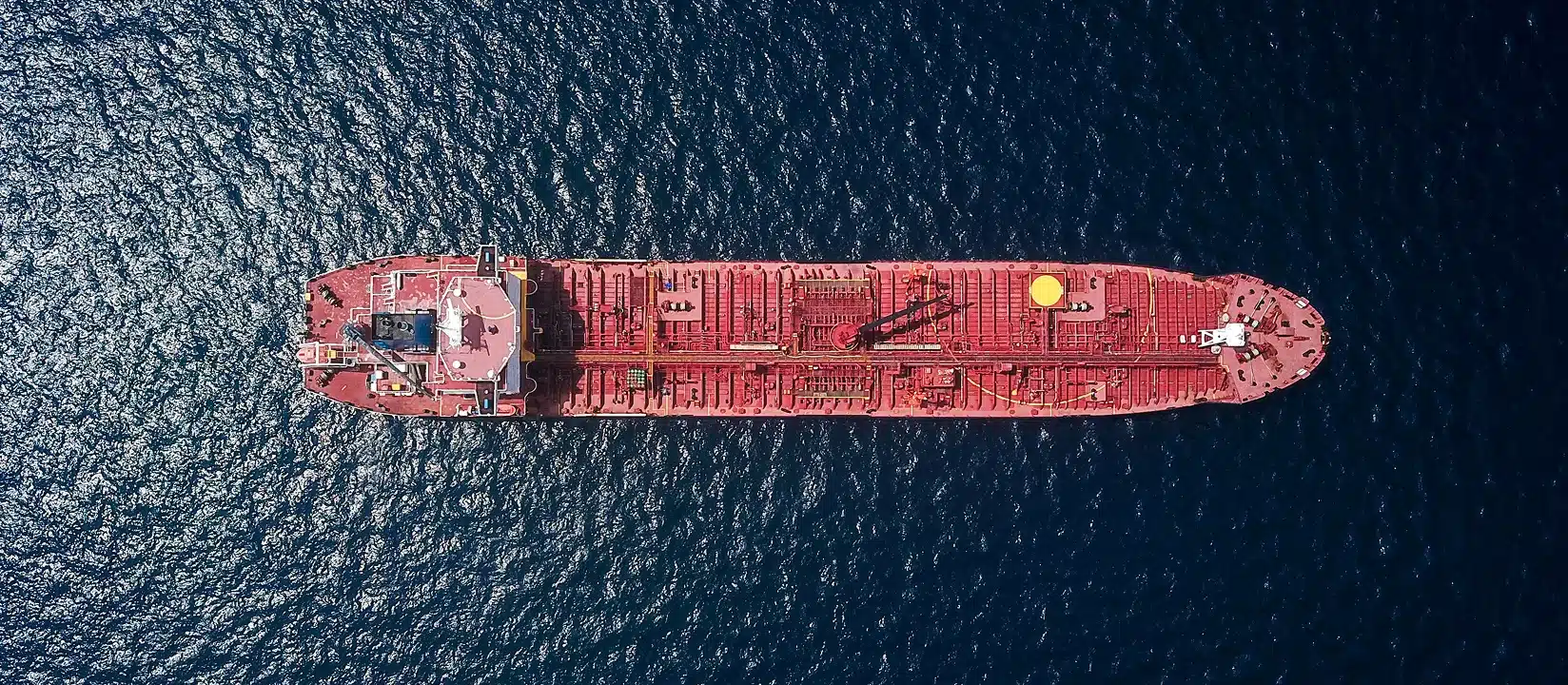 Aerial view of a large red cargo ship sailing on deep blue water