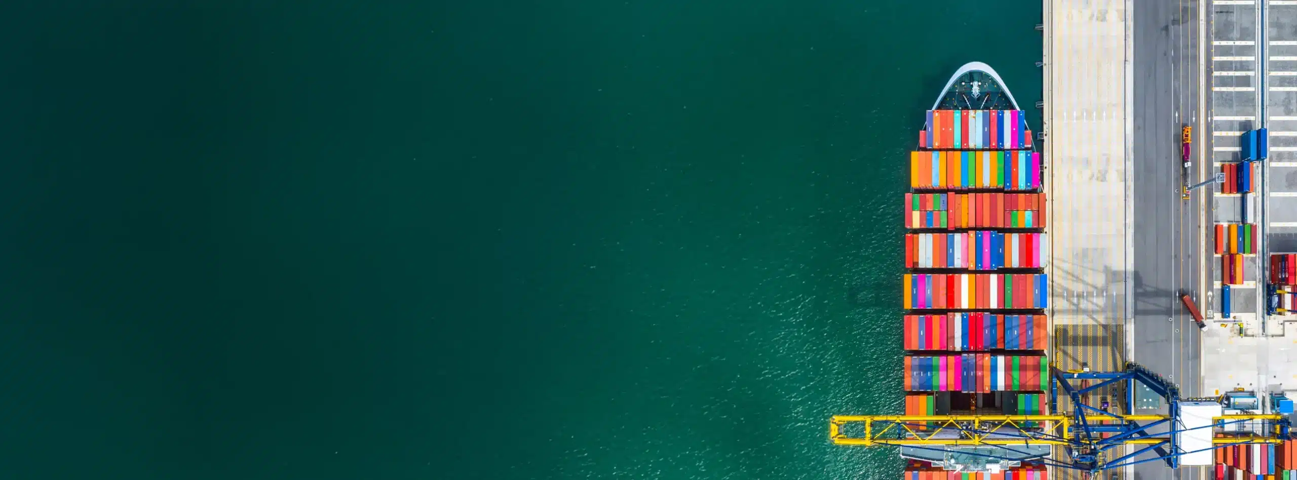 Aerial view of a cargo ship loaded with colorful containers docked at a port