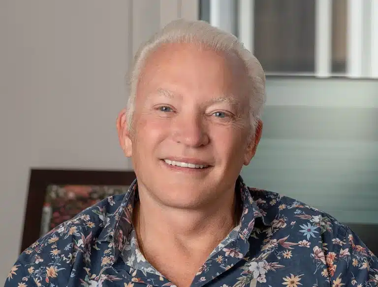Smiling older man with white hair wearing a floral shirt